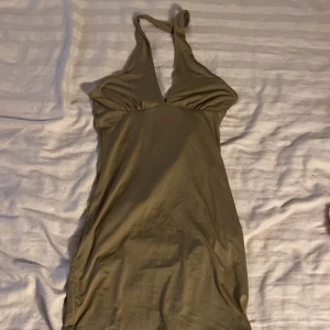 Brun kort klänning från H&M Divided - Supersnygg brun kort klänning från H&M Divided i storlek S. Klänningen har halterneck och djup v-ringning framtill. Materialet är mjukt och stretchigt.