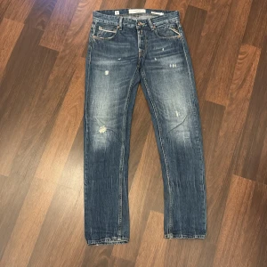 Replay Grover straight fit jeans blå - Säljer ett par Replay Grover straight fit jeans i klassisk blå tvätt med slitningar och snyggt slitna detaljer. Jeansen har raka ben, fem fickor och tydliga kontrastsömmar. Perfekta för dig som gillar en avslappnad men ändå stilren look.