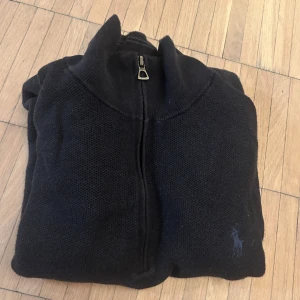 Mörkblå stickad half zip-tröja Polo Ralph Lauren - Säljer en mörkblå stickad tröja från Polo Ralph Lauren half zip. Knappast använd, inga defekter. Säljer den eftersom jag har växt ur den och använder den inte längre. Priset går att diskutera, tveka inte på att höra av dig om du har frågor!