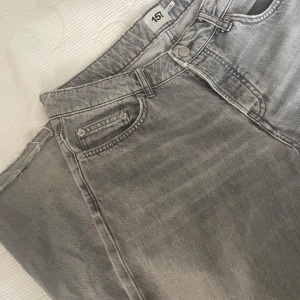 Grå jeans från 157, straight fit - Snygga grå jeans från 157 med klassisk femficksdesign och raka ben. Storlek M Jeansen har en silverfärgad knapp, dragkedja och bälteshällor. Materialet är slitstarkt denim och färgen är en cool, ljusgrå ton som passar till allt. Perfekt för dig som gillar enkel och stilren look.