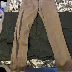 Beige Replay Anbass jeans slim fit - Säljer ett par snygga beige Replay Anbass jeans i slim fit. Klassisk femficksmodell med dragkedjegylf och diskret Replay-logga vid fickan. Jeansen har en rak och smal passform, perfekta för en clean och stilren look.