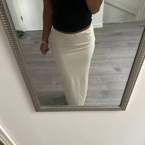Beige långkjol med enkel design - Säljer en stilren beige långkjol med rak passform och hög midja. Kjolen är enfärgad och har en mjuk, slät yta som ger en clean look. Perfekt att matcha med crop tops eller stickade tröjor för en chill vibe.
