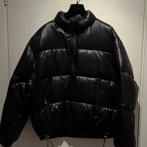 Svart pufferjacka från Celine Paris - Tjaa, jag säljer en svart pufferjacka från Celine Paris med matt glansig finish. Jackan i sig är trevlig men det blev lite problem med den förra ägaren där den inte nämnde att den var en damjacka samt storlek L. Sen dess har den hängt i garderoben cirka 3 år. Innan jag köpte jackan tog även förra ägaren bort Celine märket på yttersidan då den hade börjat att släppa, vilket kan fixas i en Celine butik. Kan även användas för en herr, men påminner om en balenciaga utseende. Begagnade ~8-12k