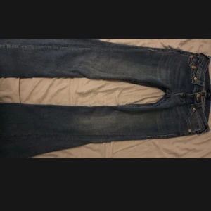 Blå Joey Low Rise Flare Jeans - Snygga blå Joey Low Rise Flare jeans från True Religion. De har en låg midja och en utsvängd stil med dekorativa ficklock bak. Perfekta för en trendig look! Säljer då jag har 2 likadana. 💗💗