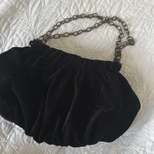 Svart sammet väska - Oanvänd!!! En svart sammet väska med grå kedja. En väska med knapp och dragkedja innuti väskan. 