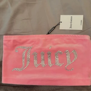Slutsåld tubtopp från Juicy Couture - Superfin rosa boob tube från Juicy Couture i mjuk velour. Framsidan har glittrande strass-stenar som bildar texten 'Juicy' i stor stil. Perfekt för dig som vill sticka ut och köra på Y2K-vibbar. Modellen är bandeau och axelbandslös. Helt slutsåld färg. 