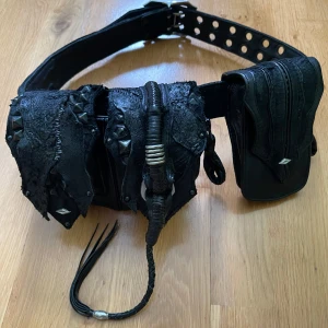 KMRii 1101 Bg01 Scorpion bälte - Svart KMRii bälte med väskor, dustbag följer med. Bältet är i size 0 vilket passar  71cm - 89cm, mittenhålet ligger på 80cm.                                                 Ungefär 2 år gammalt så det är i använt skick, bält-hålen har lite skråmor och 3 av nitarna på väskorna är lite skrapade men det märks inte.