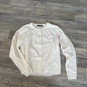 Vit stickad kofta från 157 - Säljer en vit stickad kofta från 157 i storlek S. Koftan har rund hals, långa ärmar och knappar framtill. Perfekt för lager-på-lager och har en mjuk, ribbad kant vid hals och ärmslut. Enkel och clean design som funkar till många olika stilar.