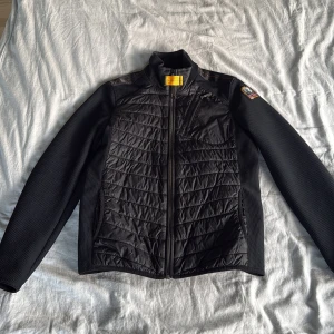 Parajumpers “Warm-Up” Cardigan, storlek 14 år (164 cm) – Nästan som ny! - Fick den i födelsedagspresent när jag fyllde 14 förra året men gillade ej den så den har mest stått i garderoben min moster köpte den åt mig på kidsbrandstore Färg svart, lätt vadderad frontpanel, trikå-ärmar och smart ficka på bröstet. I mycket fint skick. Ingen lukt, fungerar perfekt för höst och vår. Pris: 1 600 SEK (eller bud) Kan skickas (köparen står för frakt, ca 60 kr inom Sverige) eller hämtas i Västerås