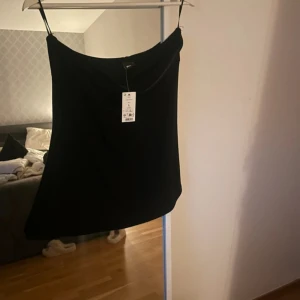 Svart tub topp - Enkel och stilren svart långkjol med rak passform. Kjolen har en slät yta och är perfekt för dig som gillar minimalistiska plagg. Passar till många olika looks och är lätt att matcha med både sneakers och boots.