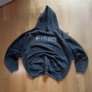  Etnies hoodie  - Svart hoodie från Etnies med stort vitt logotryck på bröstet.  Mjuk och skön, perfekt för chill eller skate. Långärmad och i en loose passform. Det finns fläckar och skav som skapar en streetkänsla, det finns också en dragsko i midjan så att det blir mycket svalare att passa tröjan som man vill. För mer information, bilder och prisdiskutering i dm.