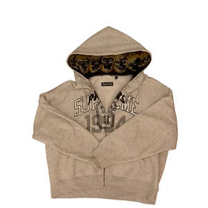 Supreme x Margiela skull zip grey/grå - Grå hoodie skull zip hoodie från Supreme x Margiela collab. Insidan av huvan har ett fett döskallemönster i svart, beige och gult. Tröjan har snörning i huvan och ribbade muddar. Perfekt för dig som vill sticka ut. Storleken är S men det är modern Oversized cropped boxy fit så passar närmre L kanske M. Kan ej garantera autenticitet på just detta klädplagget men kvaliteten är oavsett extremt bra. Inprincip helt ny, endast använd fåtal gånger. Hör gärna av er! 