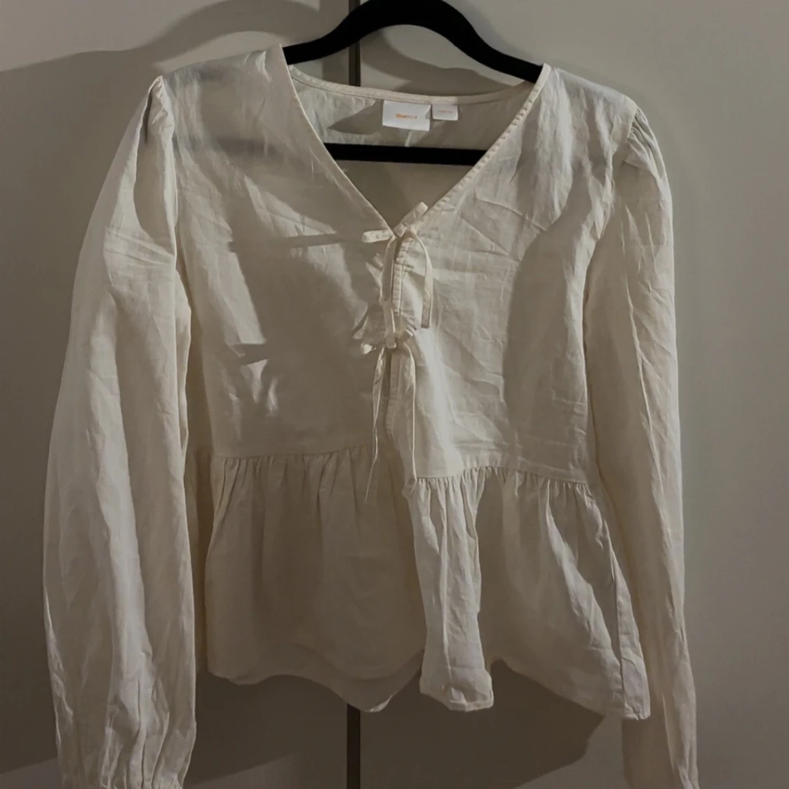 Cremevit blus med rosetter 