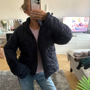 Mörkblå jacka  - Quiltad mörkblå jacka med dragkedja framtill och två fickor med knappdetalj. Jackan har en lite boxig passform och hög krage. Storlek xs men passar S också. Använd fåtal gånger. Fint skick! 