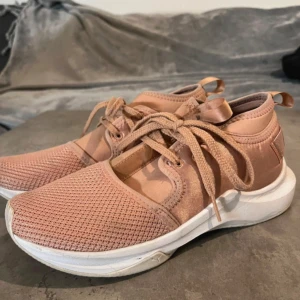 Rosa sneakers från Puma med mesh - Snygga sneakers från Puma i en ljusrosa ton med vit sula. Ovandelen är i mesh och syntet, vilket ger en sportig vibe. Skorna har snörning och Puma-logga baktill. Perfekta för dig som gillar stilrena och bekväma sneakers med modern känsla.