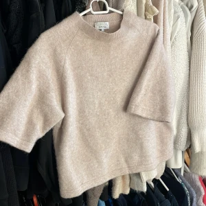 Beige stickad tröja & Other Stories - Supermysig beige stickad tröja från & Other Stories, modell med korta ärmar och rund hals. Tröjan har en loose passform och är tillverkad i ett mjukt material. Använd fåtal gånger.