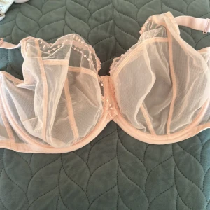 Ljusrosa bh  från Elomi - Superfin ljusrosa bh  från Elomi i transparent mesh med broderade prickar upptill. Justerbara axelband och hakknäppning bak. Materialmix av polyamid, polyester och elastan för en mjuk och luftig känsla.