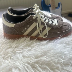 Adidas Spezial sneakers i brun/beige mocka - Säljer ett par helt oanvända Adidas Spezial sneakers i beige/brun och vitt i storleken 41. Perfekt för dig som gillar retrostil och snygga detaljer.
