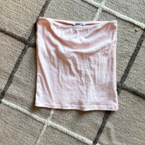 Ljusrosa tubtopp från Subdued - Enkel och snygg ljusrosa tubtopp från Subdued. Toppen är axelbandslös och har en rak, klassisk bandeau-form. Perfekt att matcha med jeans eller kjol för en clean look. Mjuk och skön i bomullsmaterial. Storleken är M med skulle sägs passar S