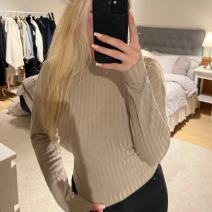Beige ribbad långärmad topp - Säljer en beige ribbad långärmad topp från ONLY i storlek XS. Toppen har en figurnära passform och är tillverkad i ett mjukt stretchigt material. Perfekt att styla med både jeans och kjol för en trendig look.