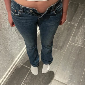 Blå bootcut jeans från Perfect Jeans - Säljer ett par klassiska blå bootcut jeans från Gina Tricot Perfect Jeans. Jeansen har normal passform, låg midja och snygga bakfickor med lock och knappar. Perfekta för dig som gillar en tidlös denimlook. Hör av er vid frågor eller om du vill ha mer bilder på plagget!💛