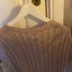 Ljusrosa kabelstickad tröja - Säljer en ljusrosa kabelstickad tröja med klassiskt flätmönster. Tröjan har rund halsringning och långa ärmar. Perfekt för lager-på-lager och passar till många olika stilar❤️