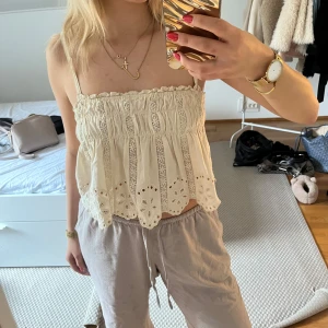 krämvit spetsig linnetopp - Säljer en söt vit linnetopp med tunna axelband och vackra spets- och broderidetaljer. Den är använd ett par gånger och i skick som ny!