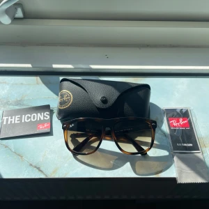 Ray-Ban boyfriend solglasögon i brun leopardmönster - Snygga Ray-Ban Wayfarer solglasögon med klassiskt leopardmönster i bruna nyanser. Bågarna är tillverkade i plast och har Ray-Ban-loggan på sidan. Kommer med originalfodral och tillbehör.