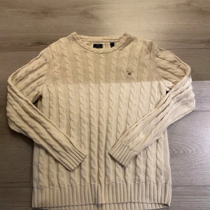 Beige kabelstickad tröja från GANT - Säljer en klassisk beige kabelstickad tröja från GANT bra kvalitet men en liten fläck på bröstet 