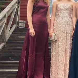 Vinröd balklänning med öppen rygg - Säljer en elegant vinröd långklänning med vacker drapering och öppen rygg. Klänningen har en figurnära passform upptill och faller snyggt ner mot golvet. Perfekt för bal eller festliga tillfällen. Jag är 168 och går ända ner i golvet och släpar ytterst lite. Den har spets i ryggen syns inte så bra på bilderna men en superfin klänning perfekt till balen.tar emot dom flesta prisförslag