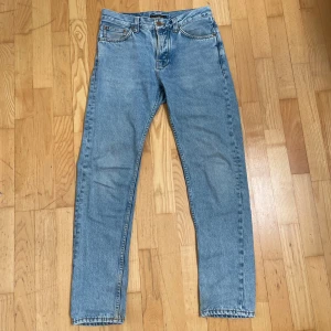 Ljusblå jeans från Nudie Jeans - Säljer ett par klassiska ljusblå jeans från Nudie Jeans med raka ben och femficksmodell. Jeansen har subtila detaljer på bakfickorna. Perfekta för en avslappnad stil. Mycket bra skick. Säljer för att de har blivit för små