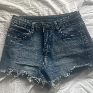 Sjukt snygga jeansshorts  - Säljer ett par jättesnygga blå jeansshorts med fransig nederkant och snygg broderad design på bakfickorna. Parfekta för sommaren!
