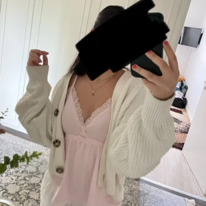 Vit stickad kofta från H&M - Säljer en vit stickad kofta från H&M i storlek XS men passar även S och M. Koftan har grovstickat material, långa ärmar och stora dekorativa knappar framtill. Slutsåld på h&ms hemsida.