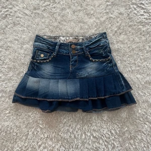 Jeanskjol med volang och nitar - En lågmidjad jeanskjol omsydd från ett par jeans. Midjemått tvärsöver -32cm, stretchig Längd - 34cm