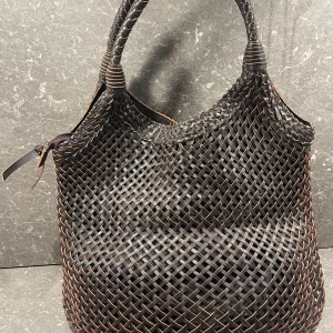 Brun axelremsväska från  Ceannis - Säljer en snygg väska från Ceannis med flätad design och två handtag. Väskan är rymlig och har dragkedja upptill samt innerfack med dragkedja. Perfekt för dig som vill ha en stilren accessoar med unik struktur.