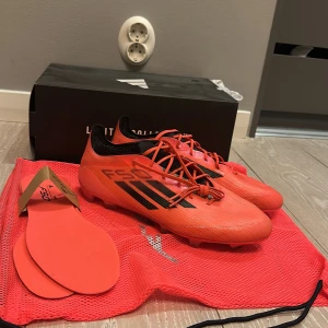 Adidas F50 fotbollsskor i orange - Säljer ett par Adidas F50 fotbollsskor i en riktigt snygg orange färg med svarta detaljer och snörning. Skorna har låg profil och är designade för fart på planen. Inkluderar extra innersulor och originalpåse. Finns kvitto dom är inte använda mycket eftersom dom är för små 