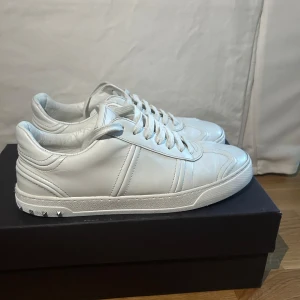 Vita sneakers från Valentino med nitar - Säljer ett par helvita sneakers från Valentino med snygga nitar på hälen. Endast en nit saknas på höger sko. Storleken är 41 men skulle kunna passa en 42. Box och snören följer såklart med. Priset är ej hugget i sten!!!