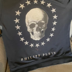 sweatshirt från Philipp Plein - Cool svart sweatshirt från Philipp Plein med stort dödskalletryck och stjärnor på framsidan. Tröjan har rund hals och tryck även på ryggen. Perfekt för dig som gillar streetwear och vill sticka ut. Liten i storlek men passar M-L utan problem