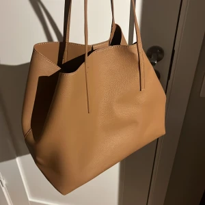 Beige handväska i skinnimitation - Kan knäppas inuti som visas på första bilden. Liknande polene väska