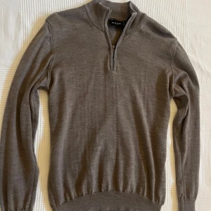 Brun merinoullströja från Sand - Brun långärmad tröja från Sand Copenhagen i 100% mjuk merinoull. Tröjan har en stilren ståkrage med half zip-dragkedja och ribbade muddar vid ärmslut och nederkant. 