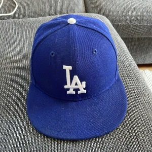 Mörkblå LA Keps - Snygg blå 59FIFTY keps från New Era med LA Dodgers-logga broderad i vitt framtill och MLB-logga bak. Klassisk rak skärm och stängd baksidar perfekt för dig som gillar snygga outfits till keps.
