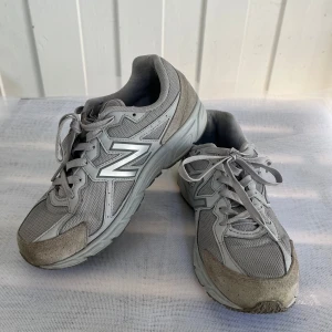 Grå New Balance sneakers - Snygga grå New Balance sneakers med klassisk silhuett och stora N-loggor på sidorna. Ovandelen är i mesh och mocka för både stil och komfort. Skorna har snörning och en rejäl, mönstrad sula som ger bra grepp. Perfekta för dig som gillar sportig och clean look. Öppen för bundles och frågor!  Man, kille, grisch, Stockholm, plagg, billigt, small, s, stil, stiligt, style, jacka, tröja, skjorta, kvalitet, märke, märkeskläder