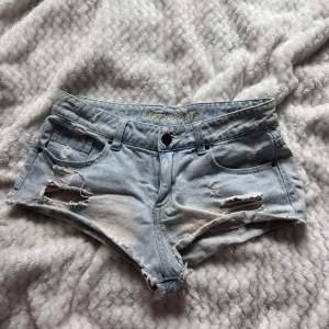 Ljusblå slitna jeansshorts lågmidjad  - Lågmidjade ljusblåa shorts med slitningar! Så snygga , passar xs-s