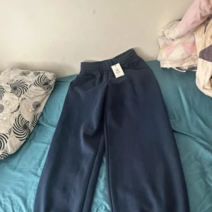 Mörkblå mjukisbyxor med resår - Mörkblå mjukisbyxor med bred resår i midjan och vid bensluten. Byxorna har en loose passform och är gjorda i mjukt material, perfekta för chill dagar. Snygg enkel design utan tryck eller mönster.