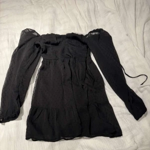 Svart kortklänning  - Supersöt svart kortklänning från H&M Divided med långa genomskinliga puffärmar och diskret prickigt mönster i tyget. Klänningen volang nertill och är tillverkad i ett lätt, flowy material som ger en luftig känsla samt knyte i ryggen 😍
