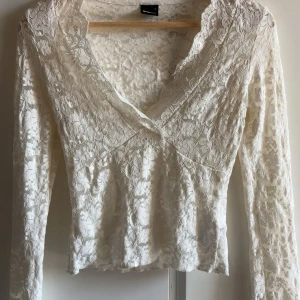 Vit spetsblus från Gina Tricot - Superfin vit blus från Gina Tricot i spets med blommigt mönster. V-ringad framtill och långa ärmar. Använd 2 gånger. Storlek S. 299 original pris 