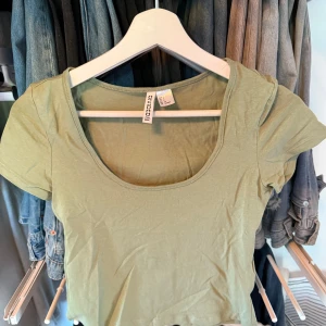 Ljusgrön topp från H&M Divided - Enkel och snygg ljusgrön topp från H&M Divided med rund, djup urringning och korta ärmar. Modellen är croppad och passar perfekt till jeans eller kjol. Använd få gånger