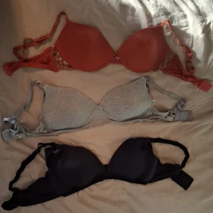 Mix av 6 bh-toppar i olika färger - Säljer ett paket med sex bh-toppar i olika stilar och färger. Innehåller tre vadderade bh:ar i korall, ljusgrå och svart samt tre mjuka, ovadderade toppar i ljusgrått och svart. Alla har justerbara axelband och klassisk knäppning bak. Perfekt för dig som vill ha variation i garderoben. Alla är mellan B-C, alla kostar 50 kr st, skriv vilka eller vilken du vill ha när du budar.