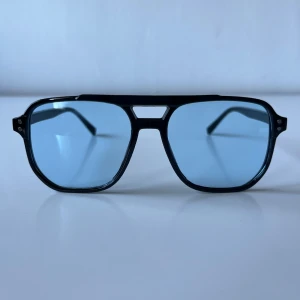 Retro solglasögon  - Retro solglasögon – svart båge med blåtonade glas Coola vintageinspirerade solglasögon med svart båge och blåa tonade linser. Sitter bekvämt och ger en stilren look. Perfekt för sommarens alla outfits! Helt nya, se bilder för detaljer.