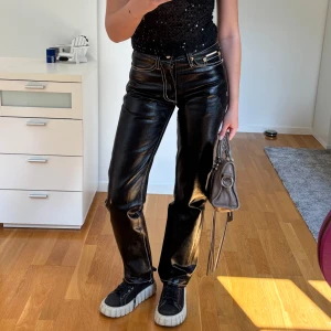 Svarta Eytys Cypress coated jeans - Säljer ett par svarta coated jeans från Eytys, modell Cypress. Byxorna har raka ben, kontrasterande vita sömmar och cool glansig finish. Klassisk femficksmodell med guldiga detaljer och normal passform. Lite slitna mellan benen och bak men syns inte när man har på dom! Original pris 2000 kr. 
